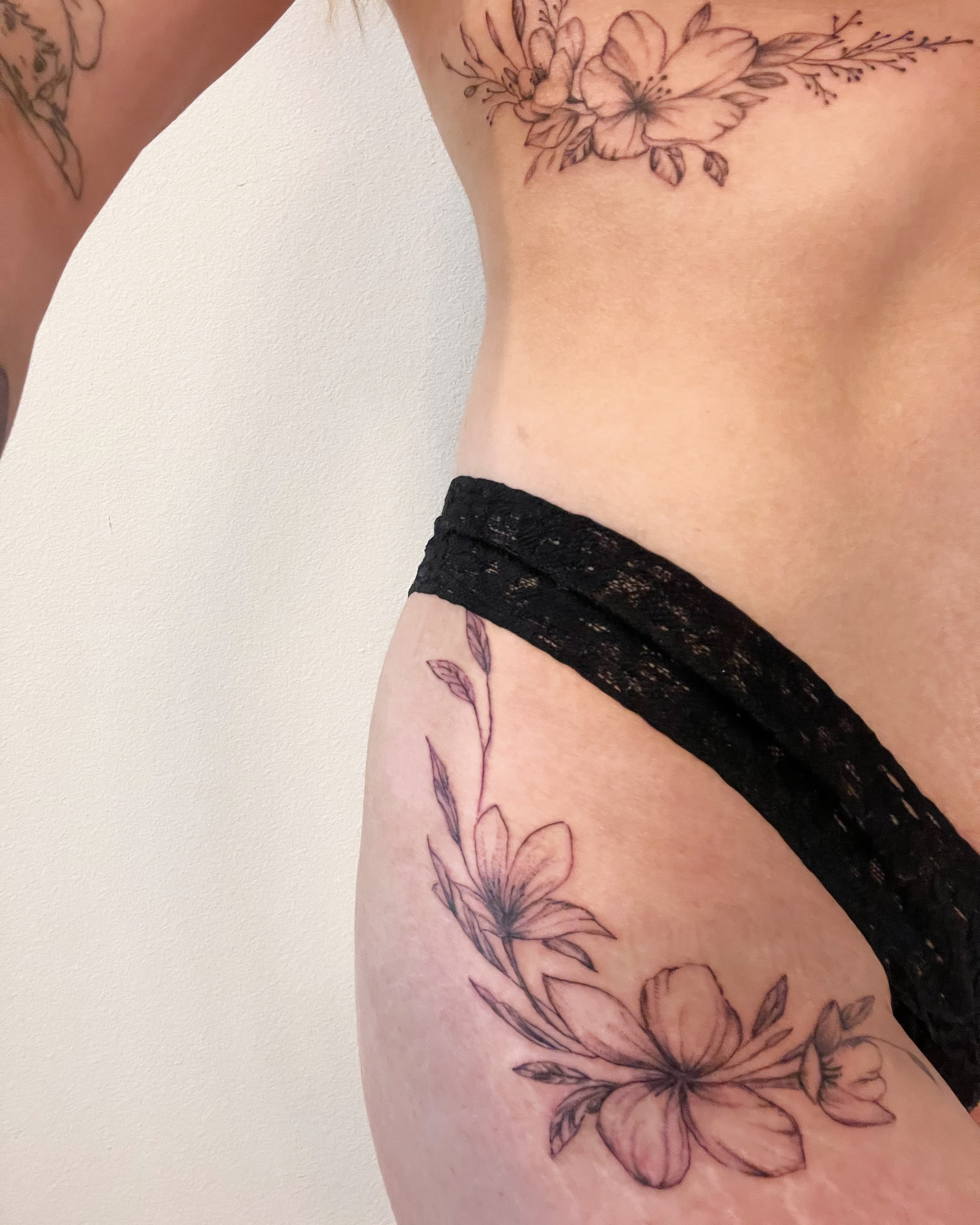 Fine line floral hip and rib tattoo with delicate botanical details by Tony Luong Maple Valley WA