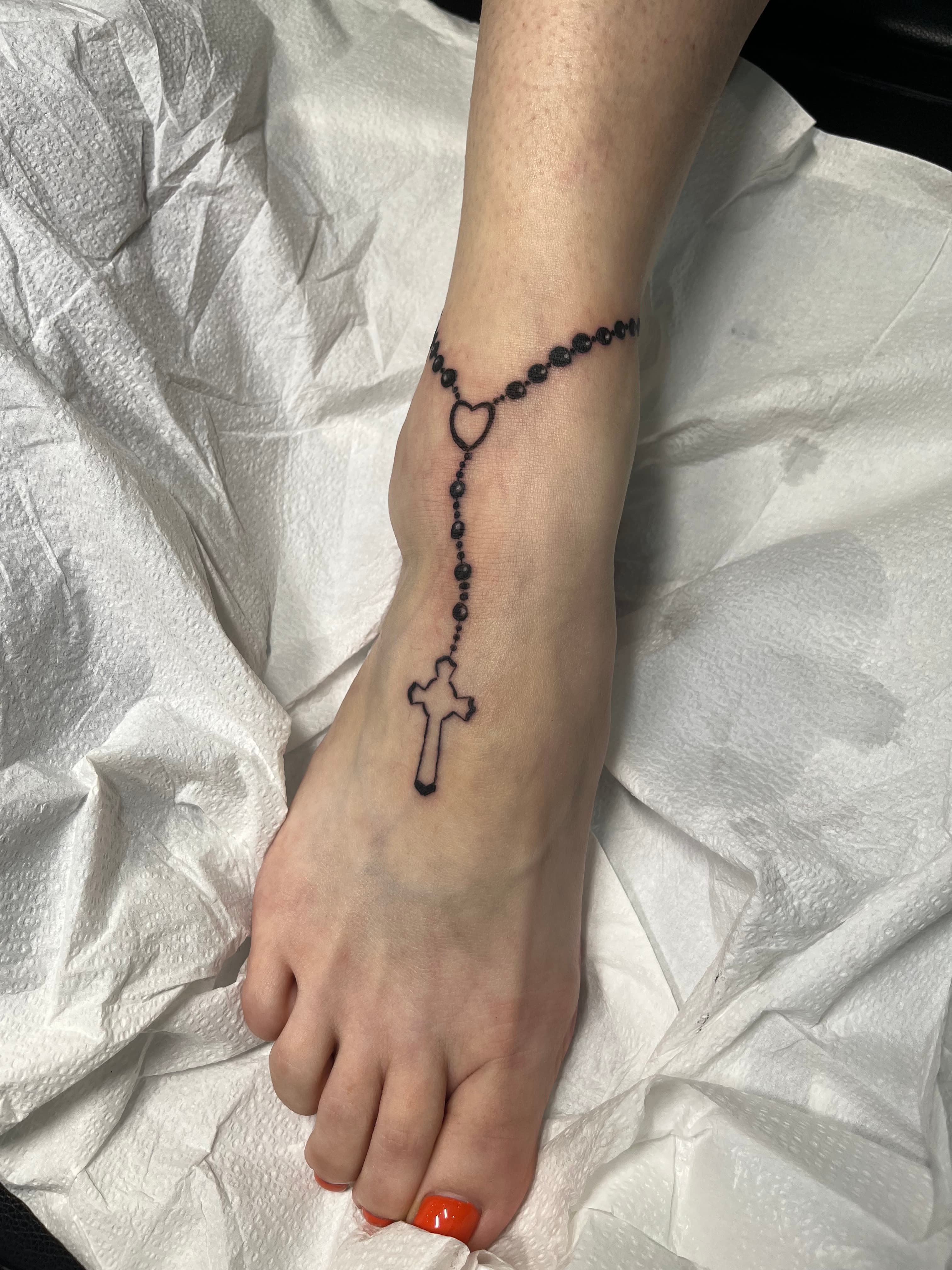 Fine line rosary cross tattoo on foot by tattoo artist Maple Valley WA