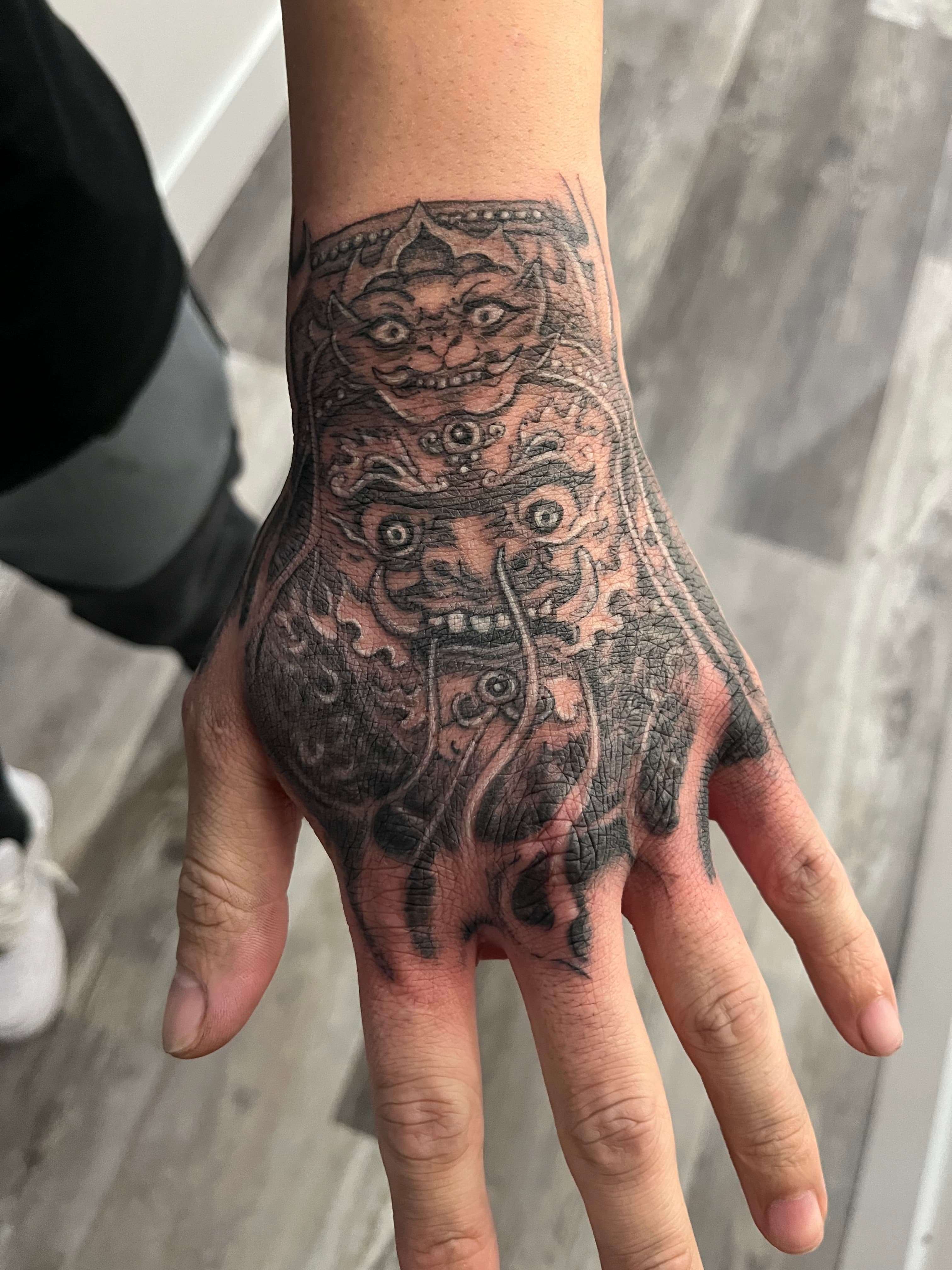 Asian-inspired foo dog hand tattoo fine line black and grey by Tony Luong Maple Valley WA